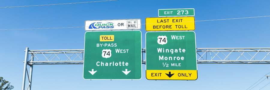 Two highway directional signs including Charlotte Toll By-Pass 74 West to Monroe Expresswway NC Quick Pass or Bill by Mail and exit 273 Wingate Monroe 74 West Last Exit Before Toll
